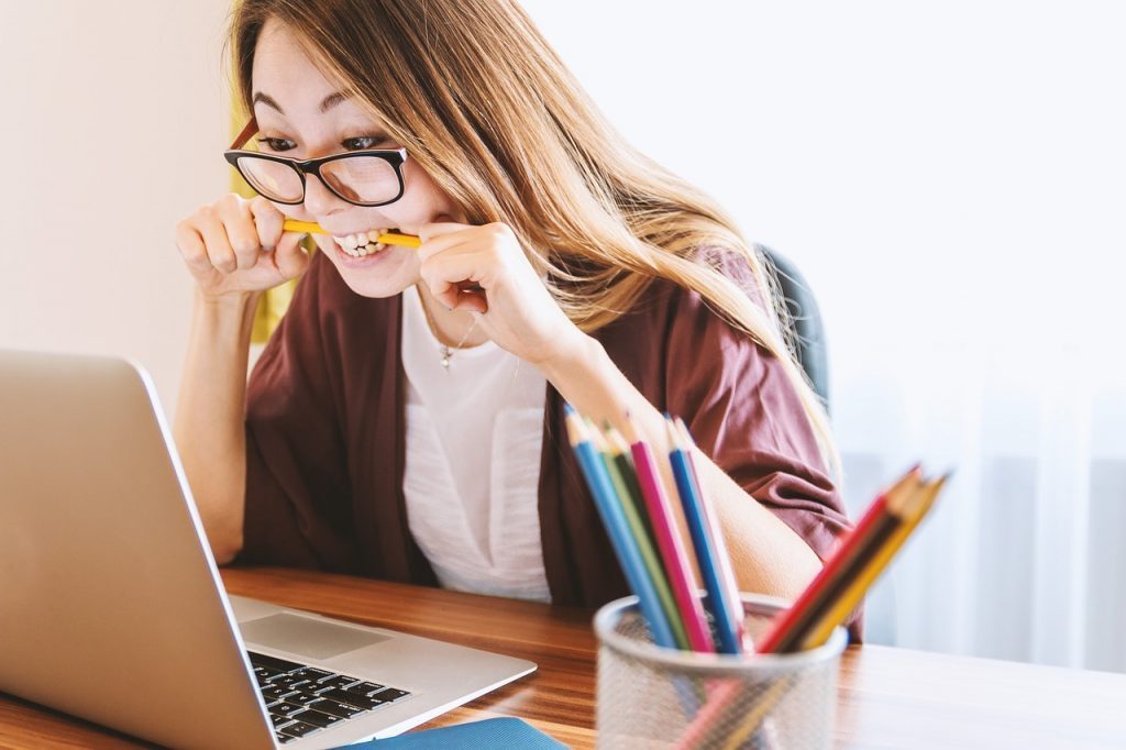 Woman In Front of Laptop Bites Pencil